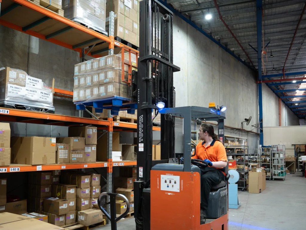 Forklift moving stock between warehouse racks