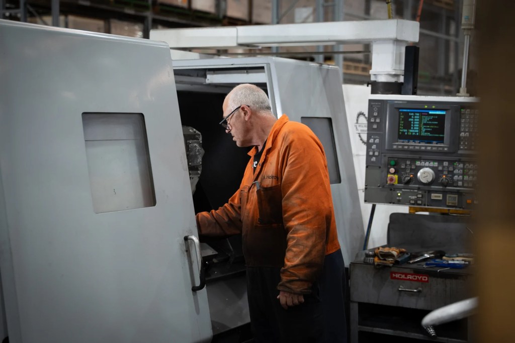 A Holroyd machinist loading a part into a CNC lathe